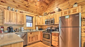 A wooden cabin kitchen with wooden cabinets, stainless steel appliances, a dishwasher, and a refrigerator. - 3 Mi to Dollywood: Hot Tub Hideaway in Smoky Mtns (Sevierville)