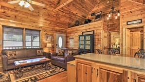 A wooden cabin interior with a living room, kitchen, and dining area. - 3 Mi to Dollywood: Hot Tub Hideaway in Smoky Mtns (Sevierville)