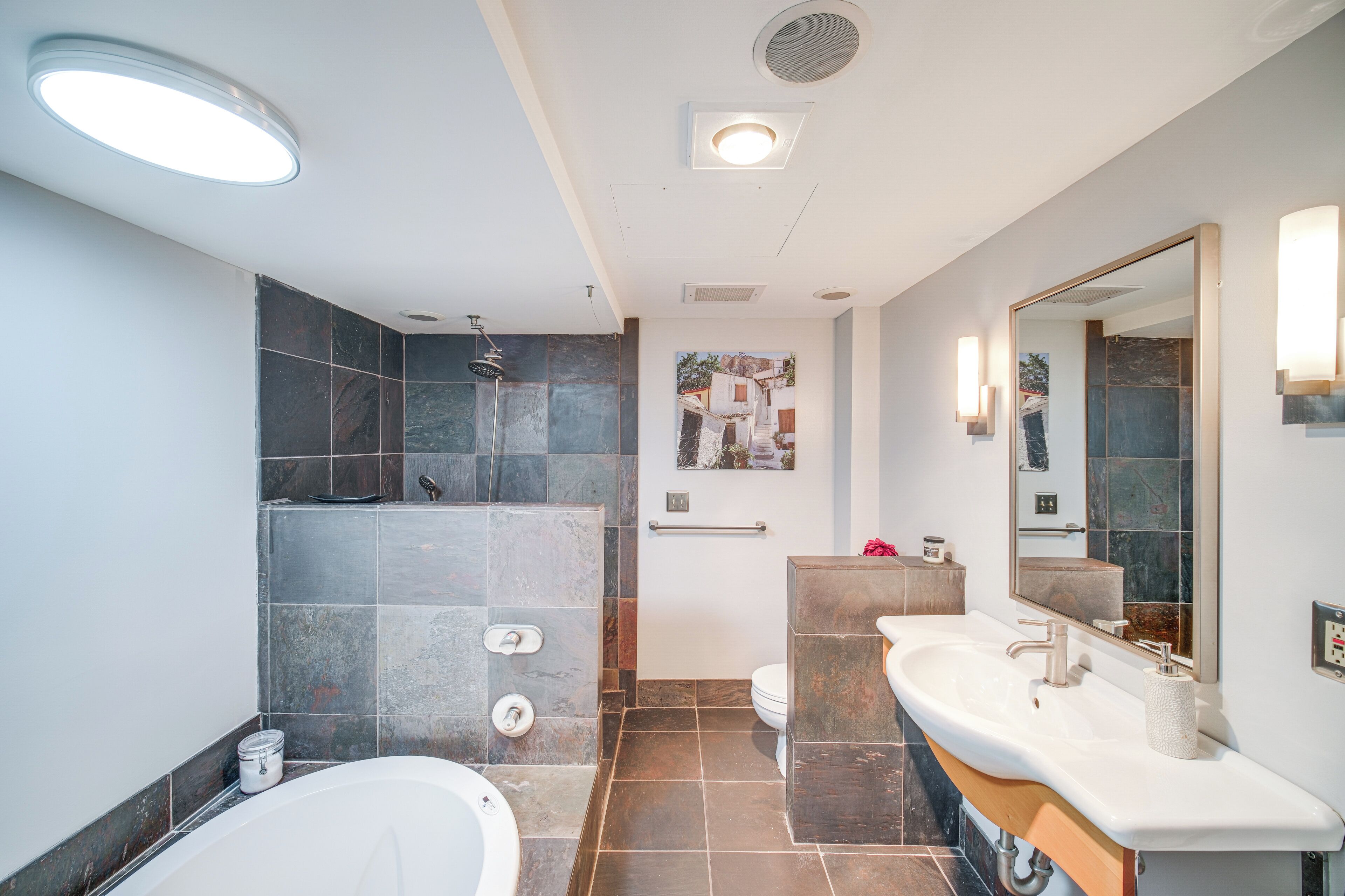 A modern bathroom with a bathtub, a shower, and a vanity with a mirror.