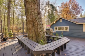 Eine Holzterrasse mit Bänken, einem Tisch und einem Haus mit blauer Fassade.