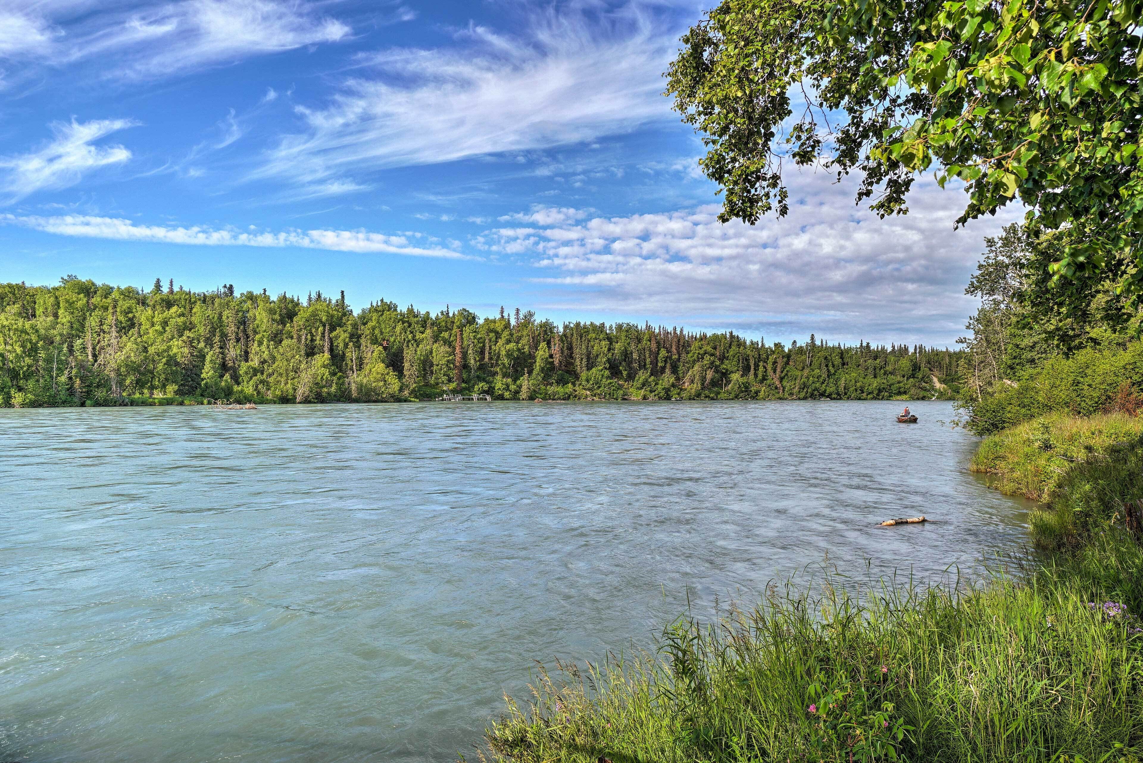 A river with a forested bank and a boat in the distance.
