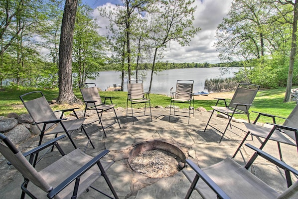 An outdoor seating area with chairs arranged around a fire pit, overlooking a lake. - Stunning Crosslake Cabin w/ Deck and Lake Views! (Crosslake)