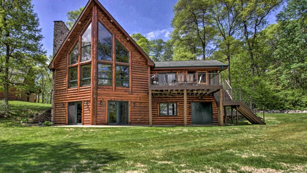 A log cabin with a large glass front, a balcony, and a stone chimney. - Stunning Crosslake Cabin w/ Deck and Lake Views! (Crosslake)