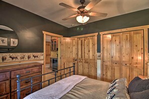 A bedroom with a bed, wooden wardrobe, a dresser, a ceiling fan, and a wall with animal prints. - Stunning Crosslake Cabin w/ Deck and Lake Views! (Crosslake)