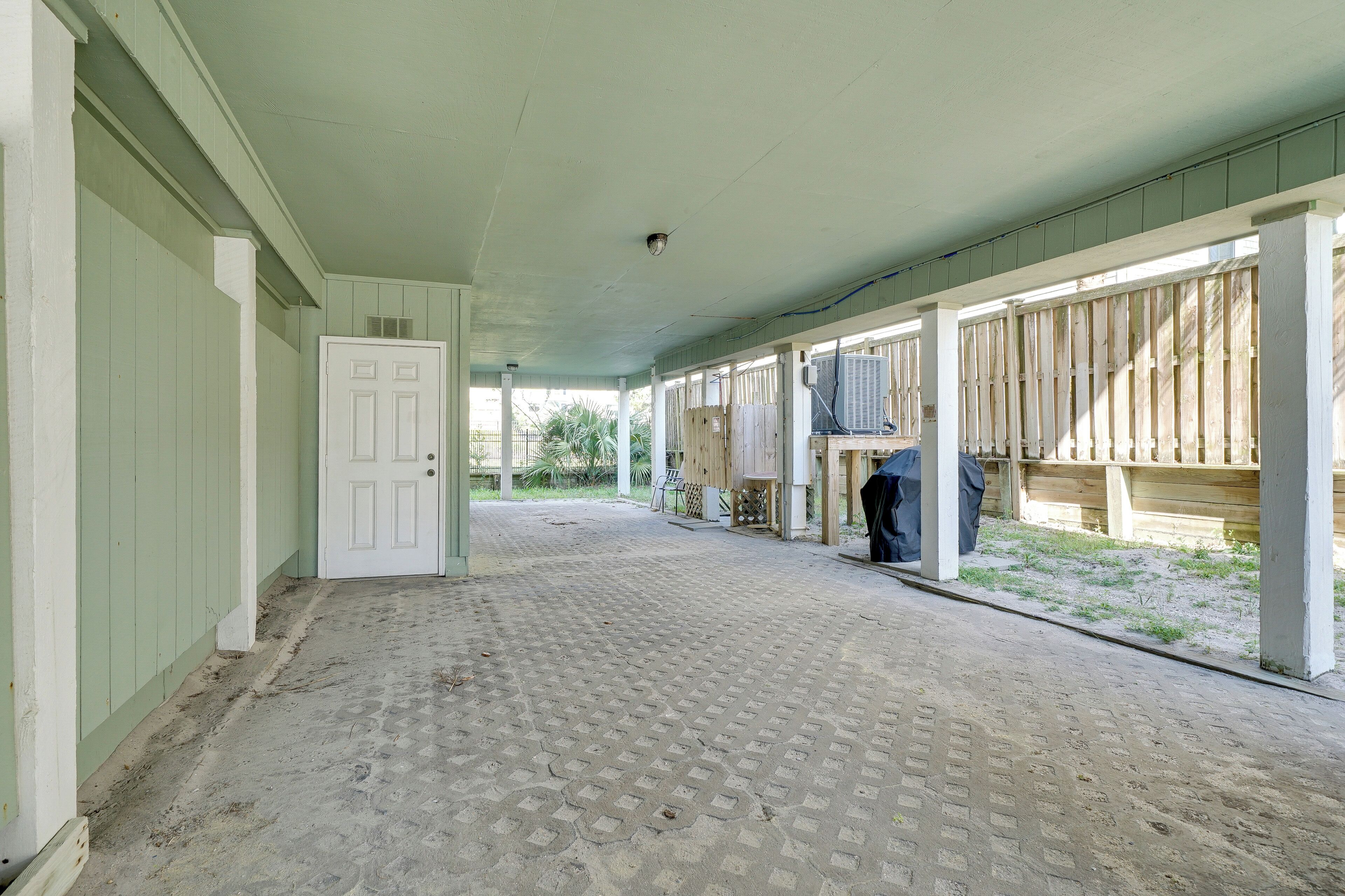 A covered corridor with a patterned floor, wooden walls, and a white door.