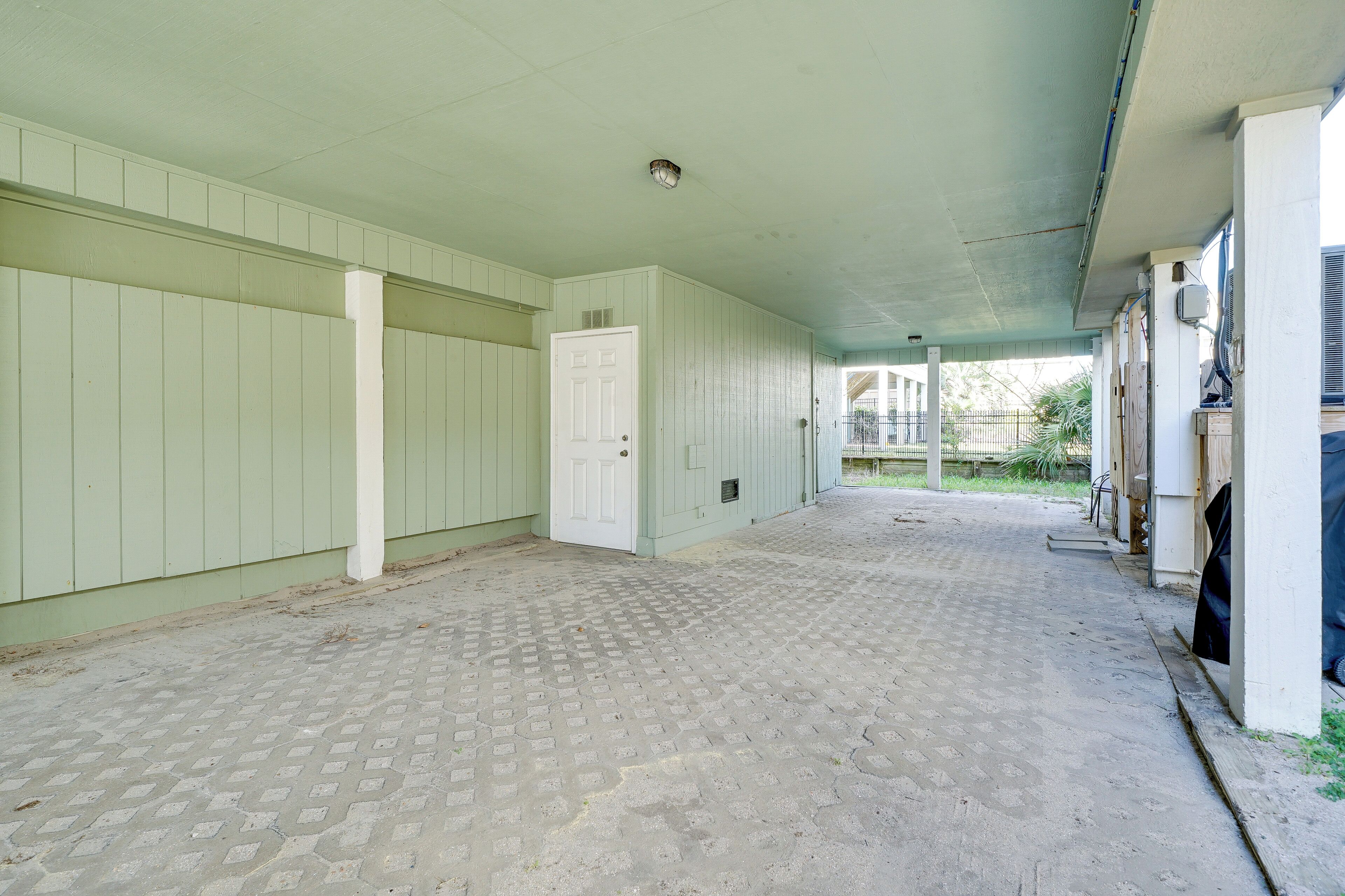 A covered outdoor area with a tiled floor, a white door, and a green wall.