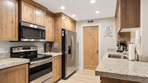 A kitchen with wooden cabinets, stainless steel appliances, granite countertops, and a stainless steel sink.
