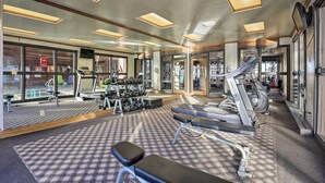 A gym with exercise equipment, a mirror, and a patterned carpet.