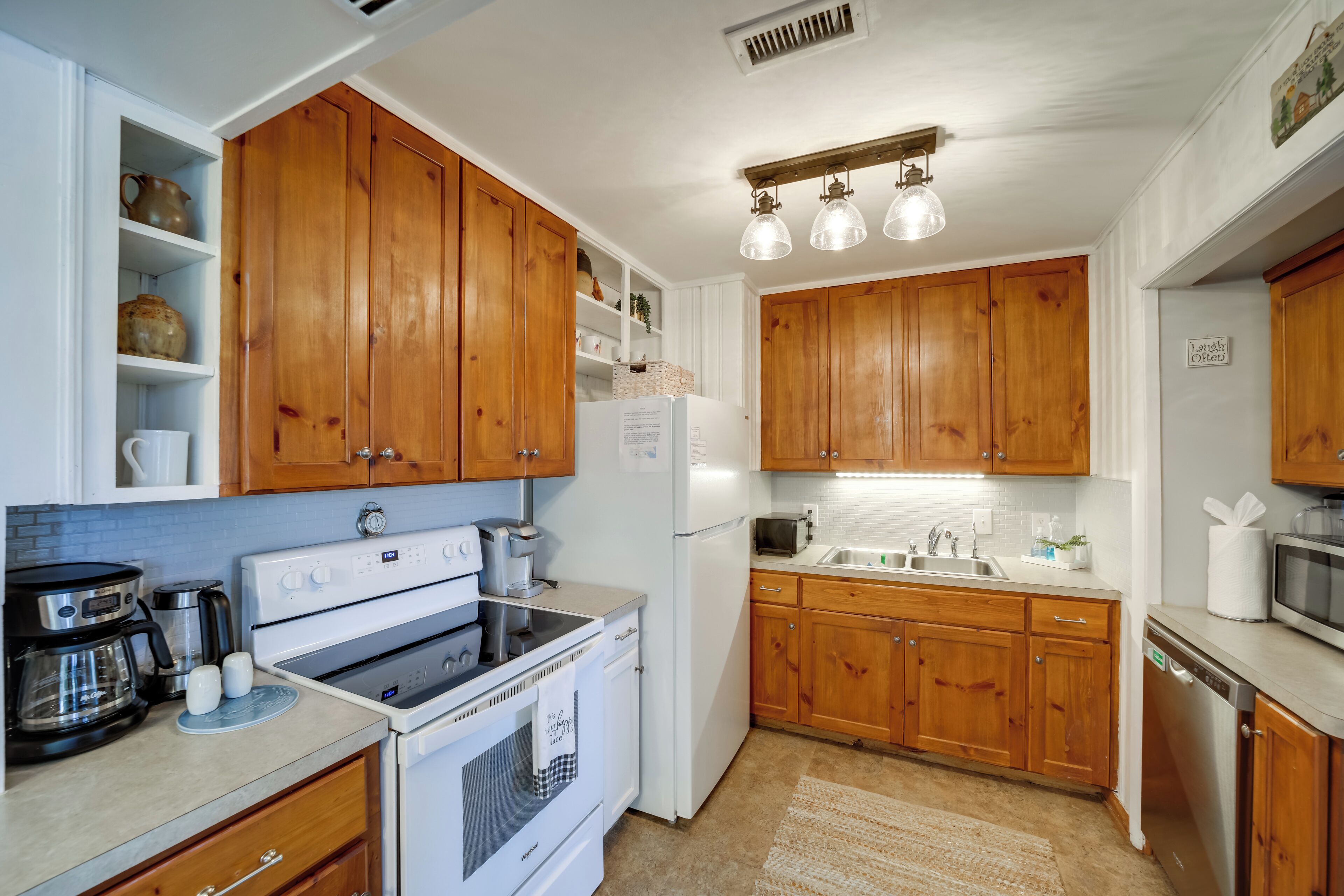 A kitchen with wooden cabinets, white appliances, and a built-in shelf with kitchenware.