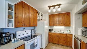 A kitchen with wooden cabinets, white appliances, and a built-in shelf with kitchenware.