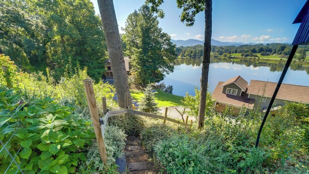 Un escalier en bois menant à une maison d’où l’on peut admirer un lac et des montagnes.