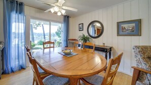 Une salle à manger avec une table en bois, des chaises, un ventilateur de plafond et une vue sur l’extérieur.