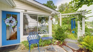 Une maison avec une porte bleue, une guirlande et un jardin agrémenté d’une chaise et d’une table bleues.
