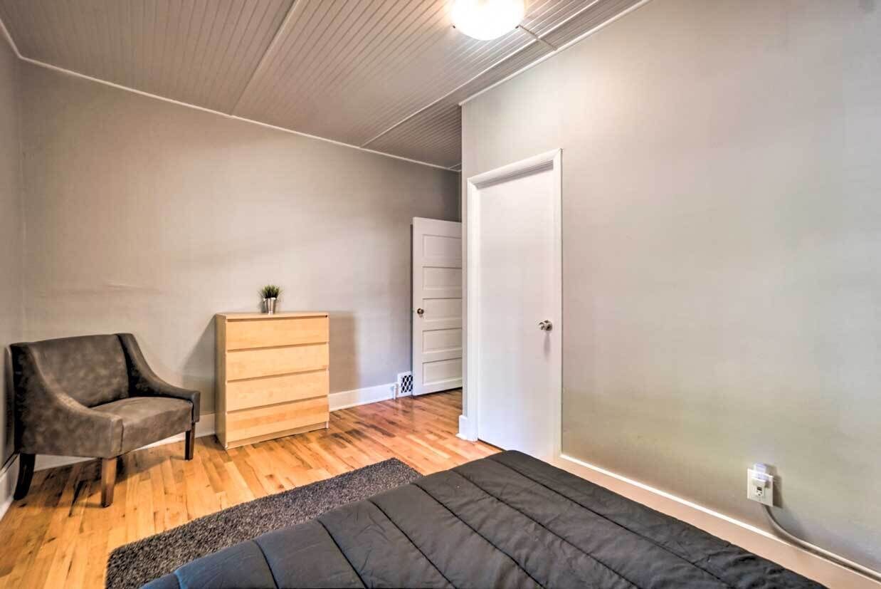 A bedroom with a bed, a chair, a dresser, and a door.