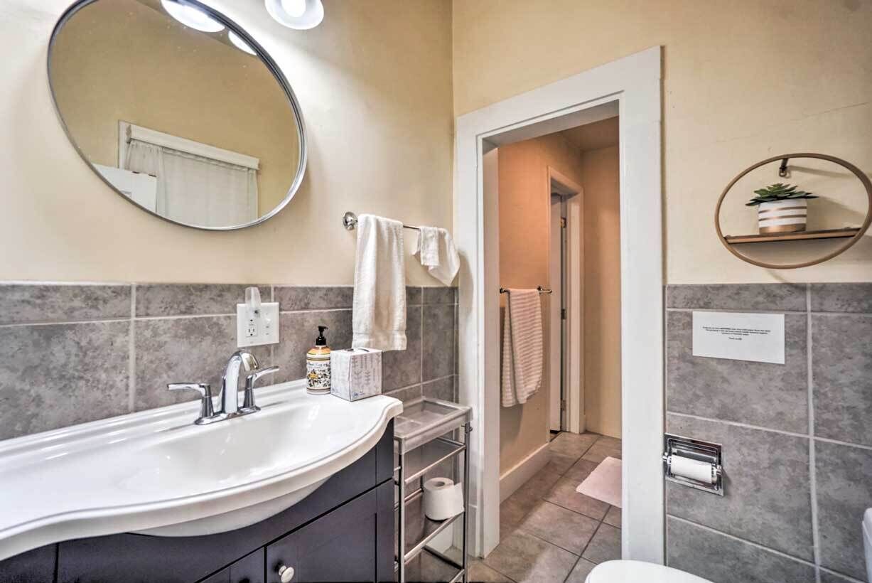 A bathroom with a large sink, mirror, towel rack, and a small shelf with a plant.
