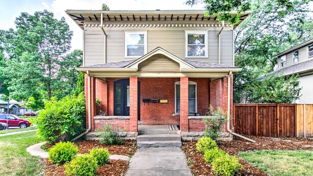 A two-story house with a front porch, brick facade, and a small front yard with shrubs and mulch. - Historic Redstone w/ Large Backyard, Walk To Csu! (Fort Collins)