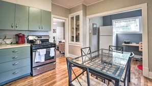 A compact kitchen with a stove, oven, and cabinets, a glass dining table, and a refrigerator. - Historic Redstone w/ Large Backyard, Walk To Csu! (Fort Collins)