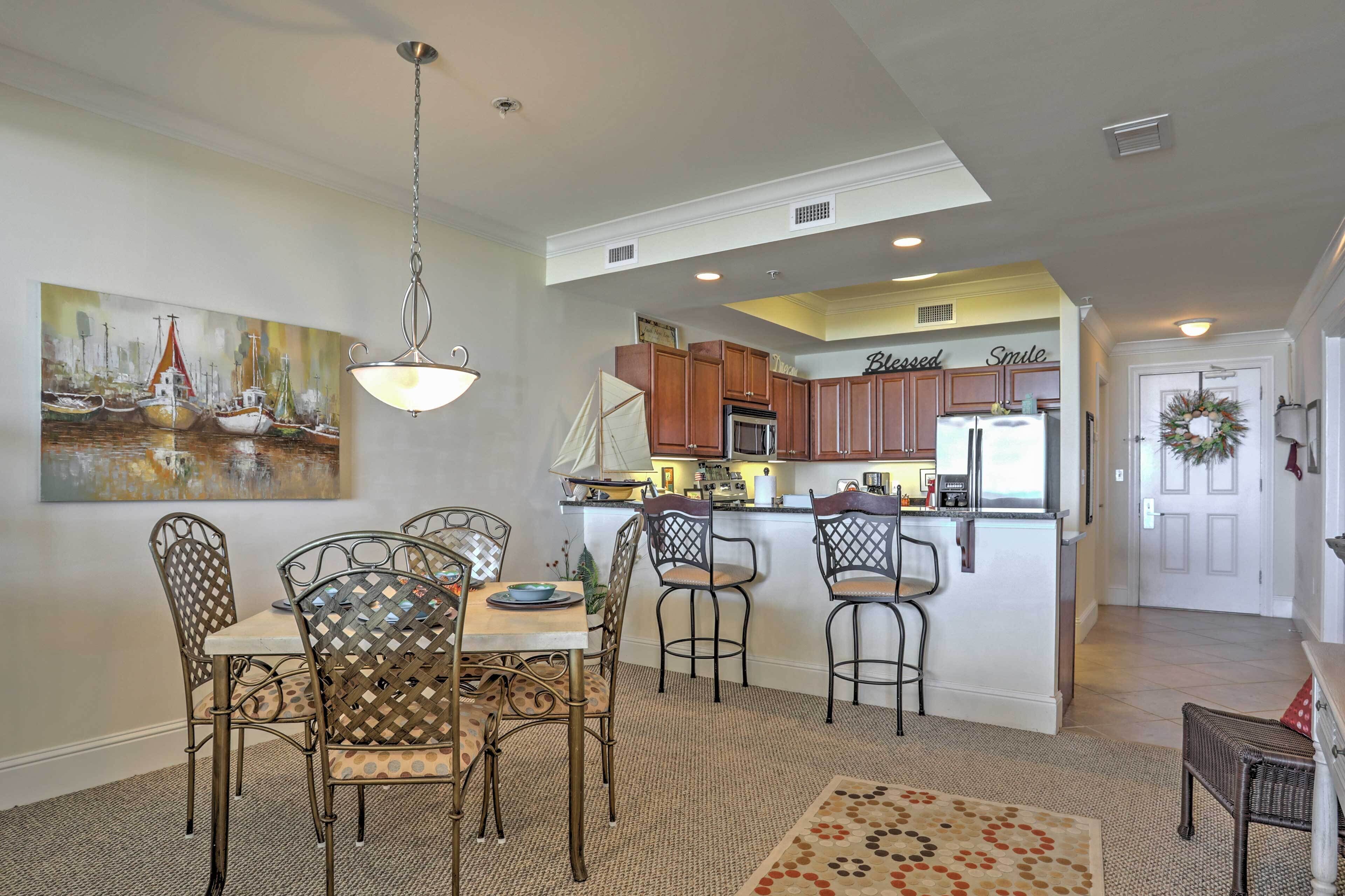 A dining area with a table and chairs, a kitchen with wooden cabinets, and a painting on the wall.
