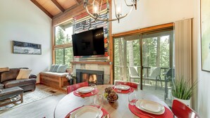 A dining area with a wooden table set for four, surrounded by red chairs, a fireplace, and a television mounted on a wall above the fireplace. - 1 Mi to Northstar Skiing/snowboarding: Cozy Condo (Truckee)