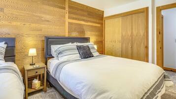 Un dormitorio con cabecera de madera, una mesita de noche con lámpara, cama con ropa de cama a rayas y un armario.