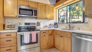 Una cocina moderna con armarios de madera, electrodomésticos de acero inoxidable y ventana con vistas a un paisaje natural.