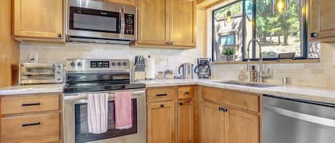 Une cuisine moderne avec des meubles en bois, des appareils électroménagers en acier inoxydable et une fenêtre donnant sur un paysage naturel.