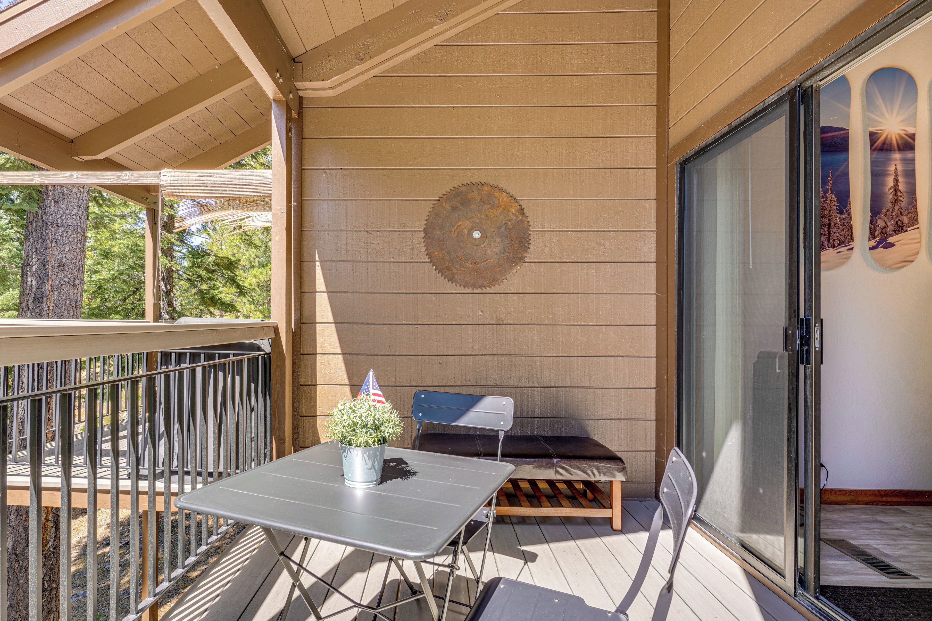 A covered outdoor seating area with a table and chairs, a potted plant, and a decorative metal piece on the wall.
