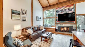 A cozy living room with a fireplace, a large window, and a television mounted on the wall. - 1 Mi to Northstar Skiing/snowboarding: Cozy Condo (Truckee)