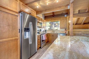 A modern kitchen with stainless steel appliances, wooden cabinets, and a large island with a marble countertop. - 1 Mi to Northstar Skiing/snowboarding: Cozy Condo (Truckee)