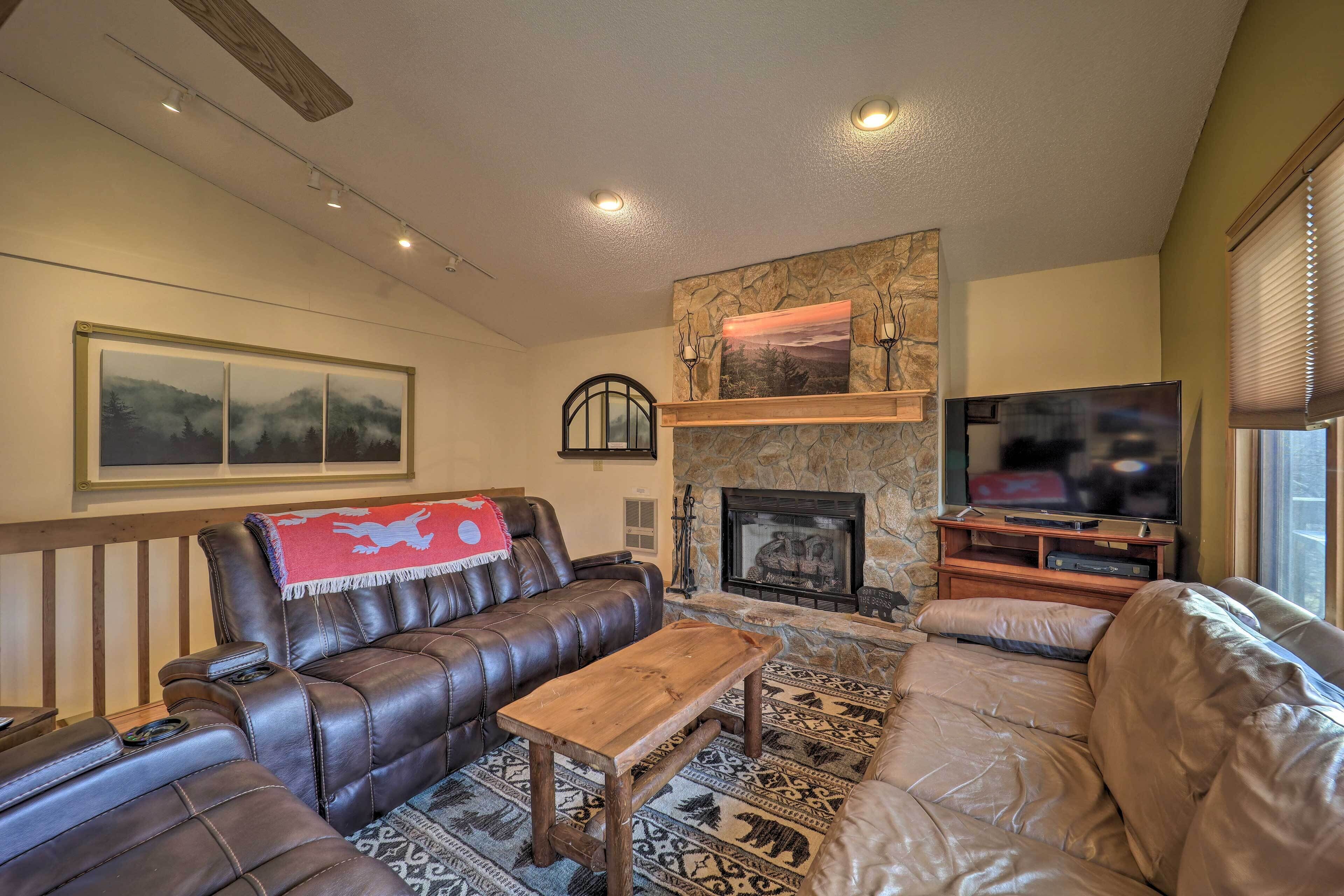 A cozy living room with a leather sofa, a wooden coffee table, a fireplace, and a television on a stand.