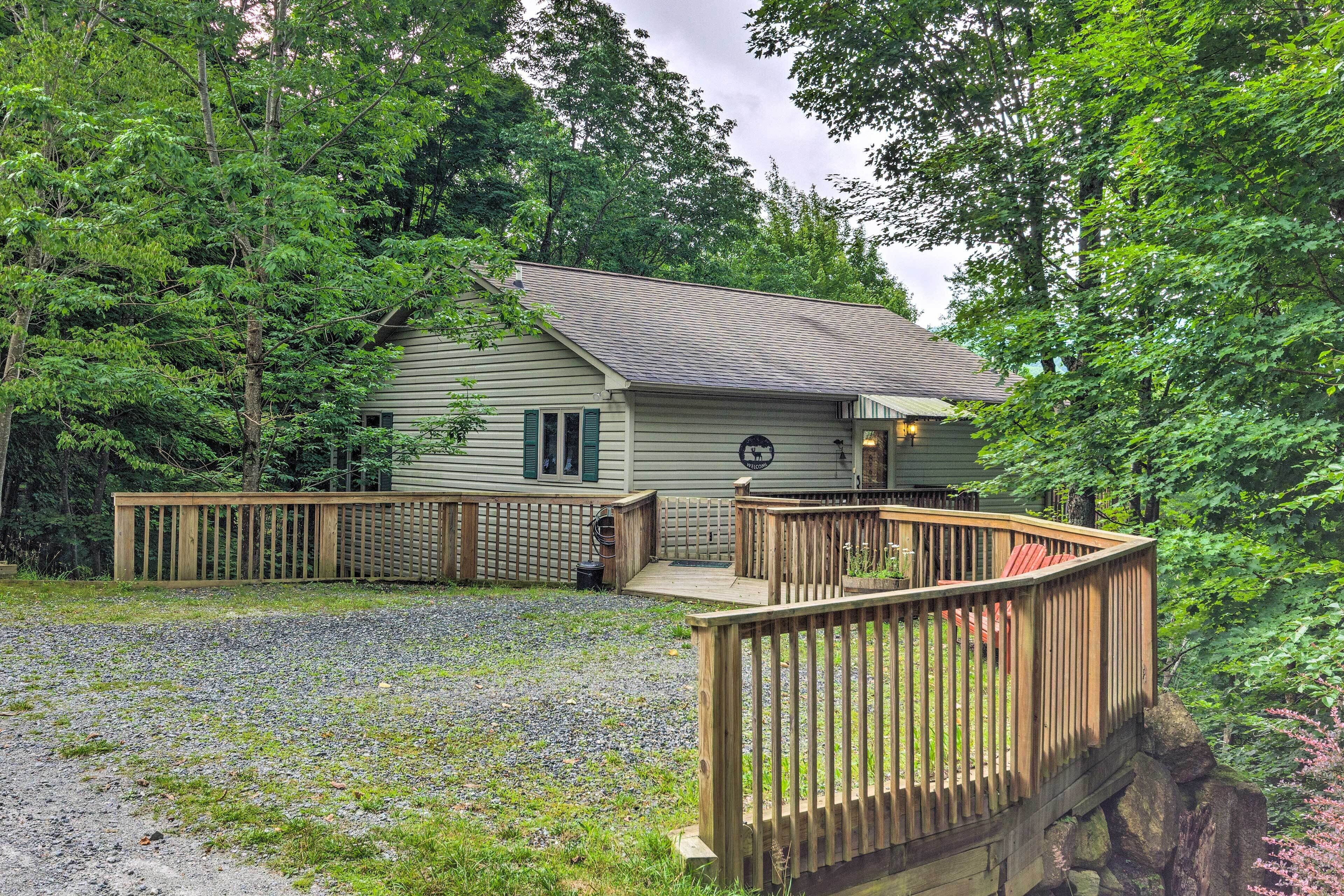 Une cabane dotée d’une terrasse, entourée d’arbres.