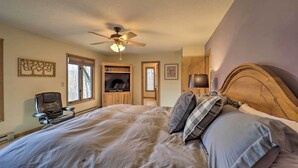 Ein Schlafzimmer mit einem großen Bett, einem Deckenventilator, einem Fernseher und einem Sessel.
