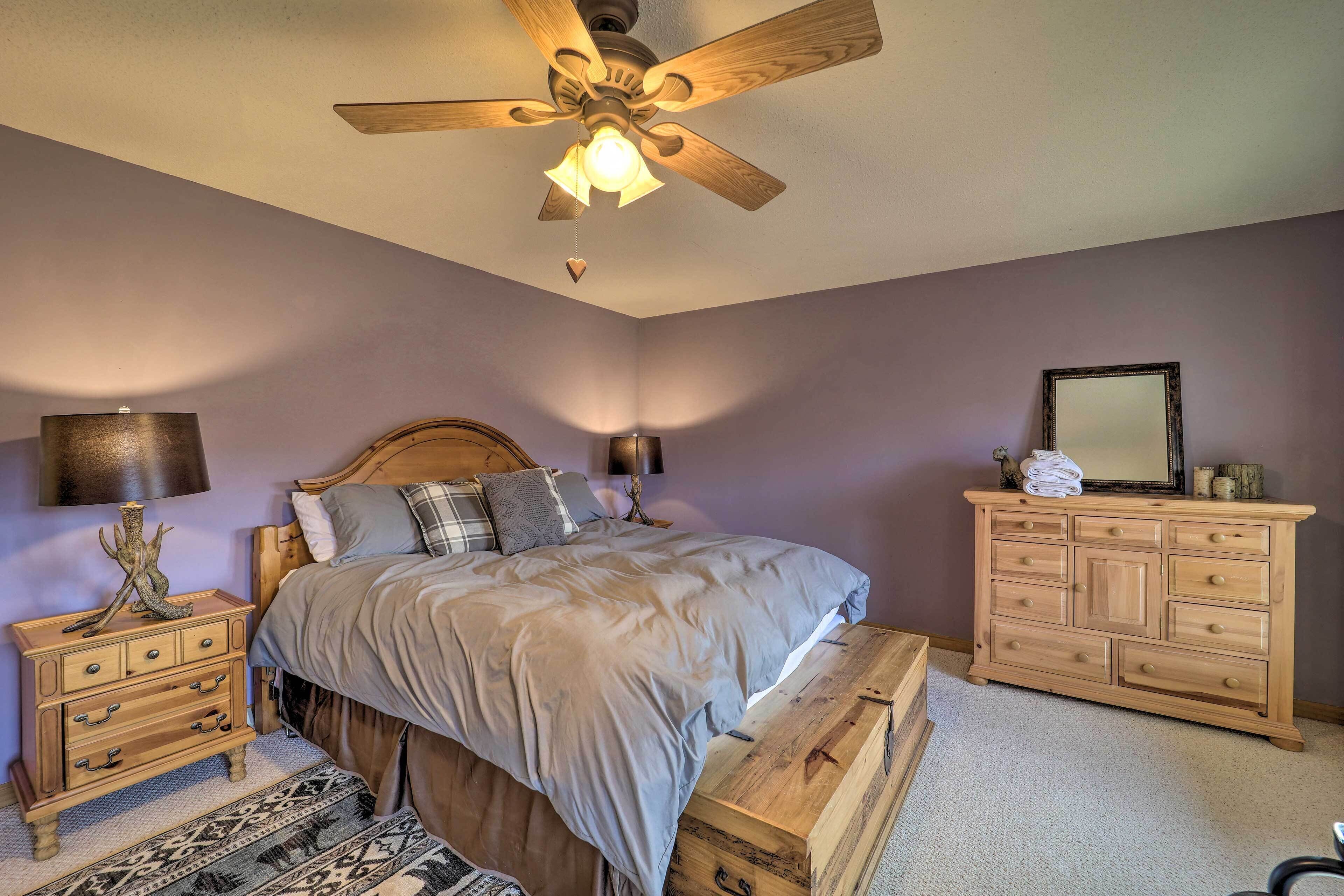 Un dormitorio con cama, cómoda de madera, mesitas de noche y ventilador de techo.