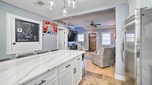 A modern kitchen with a marble countertop, white cabinetry, and a stainless steel refrigerator. - Modern Retreat ~ 1/2 Mi to Bryant-denny Stadium (Tuscaloosa)