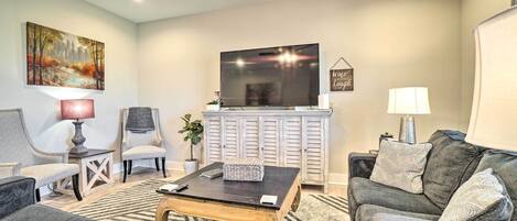 A living room with a TV, two armchairs, a sofa, a coffee table, and a cabinet.