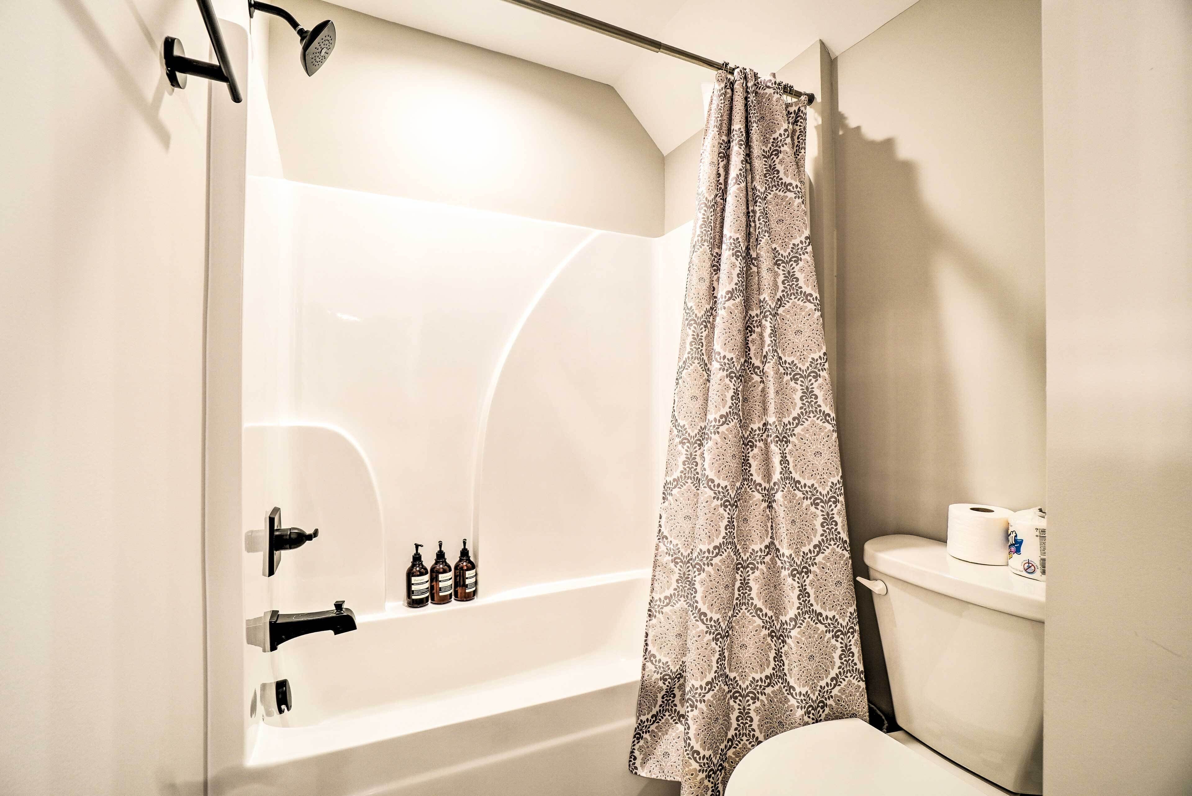 A bathroom with a bathtub, toilet, and shower curtain.