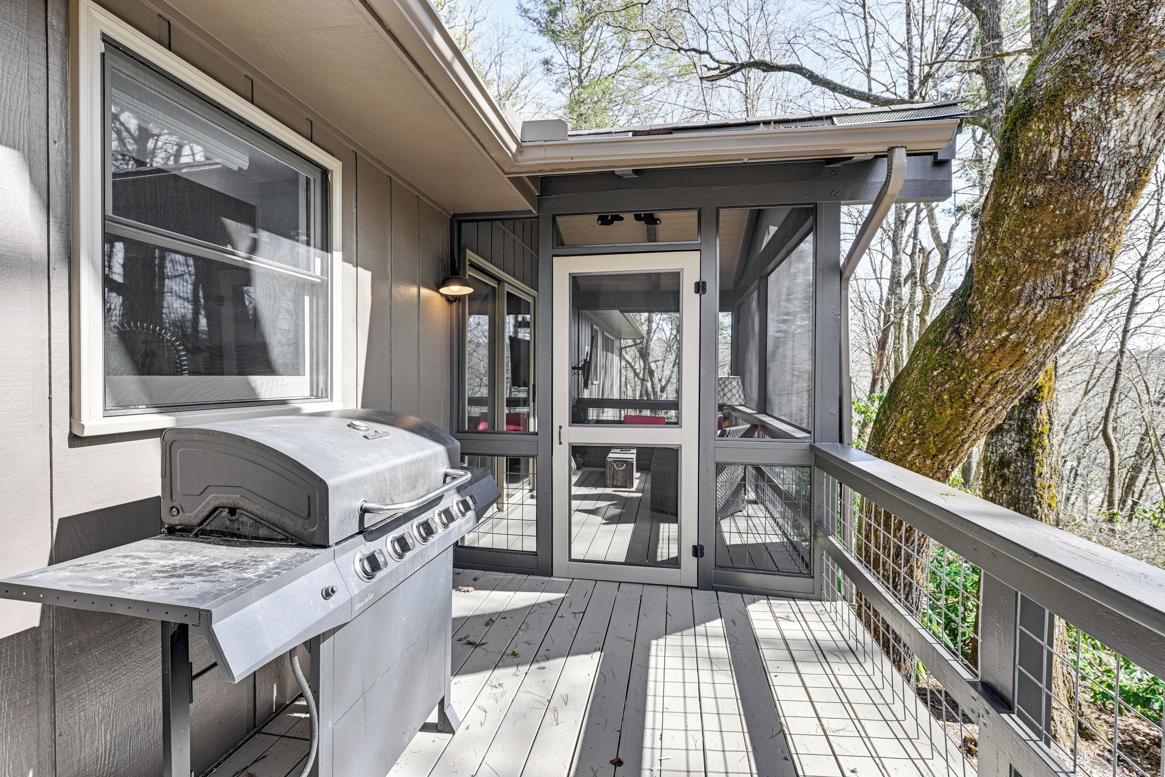 A covered deck with a grill and a door leading to an outdoor area.