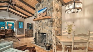 A cozy living room with a stone fireplace, wooden ceiling beams, and a chandelier. - Walk to Main St: Highlands Cottage w/ Fireplace (Highlands)