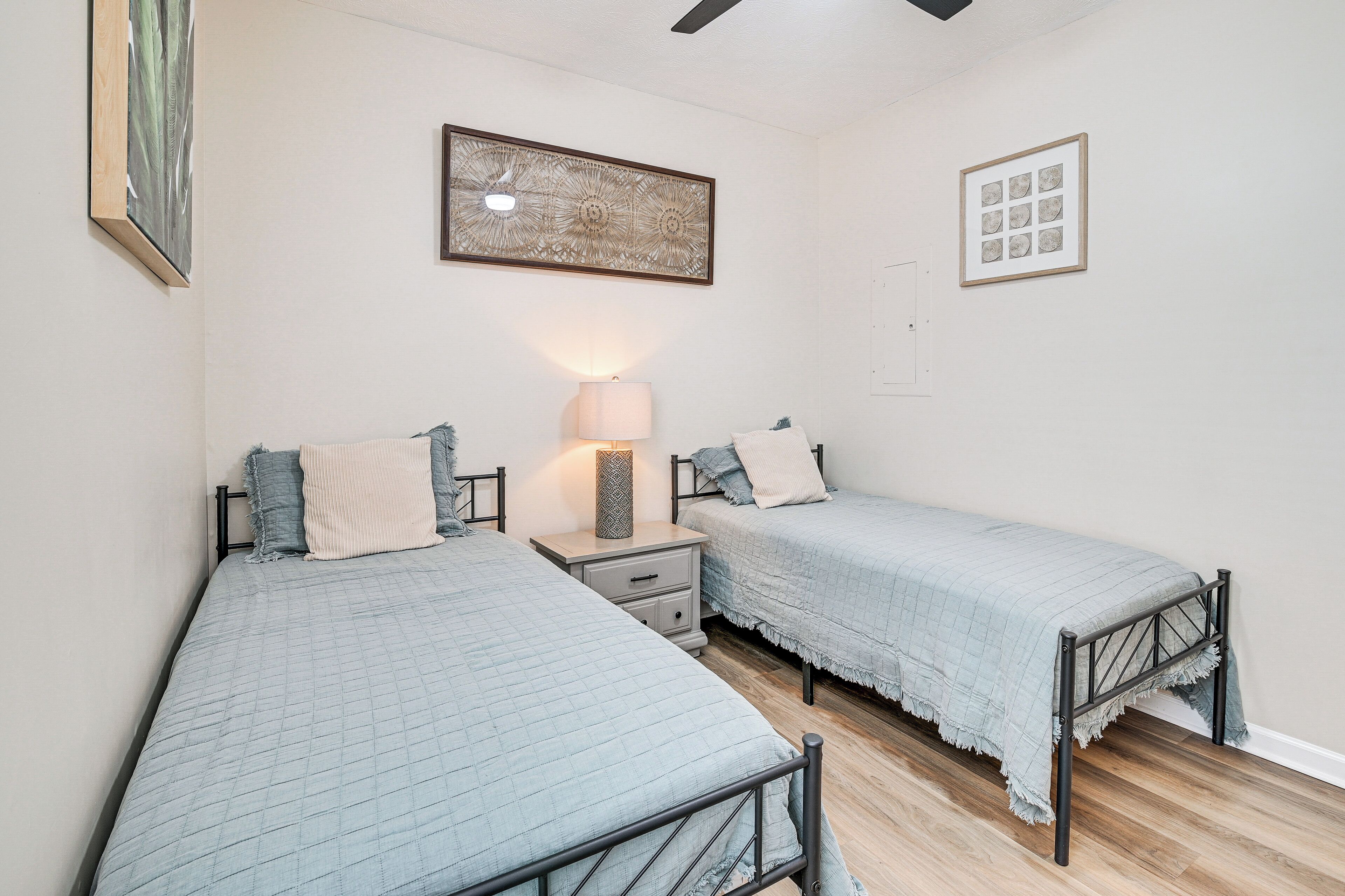 Una camera da letto con due letti singoli, un comodino, una lampada e un quadro appeso al muro.
