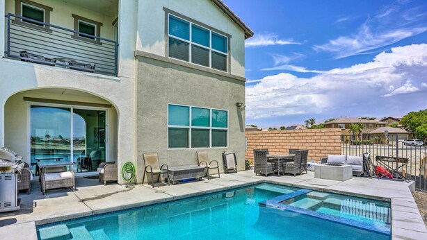 Une maison à deux étages avec une piscine, du mobilier d’extérieur et un espace barbecue.