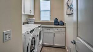 Une buanderie équipée d’un lave-linge et d’un sèche-linge à chargement frontal, d’une fenêtre et d’un évier.