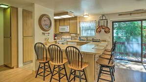 A kitchen with wooden cabinets, a microwave, and a large island with bar stools.