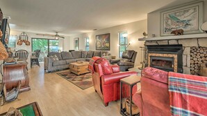 A spacious living room with a fireplace, a sofa, a red leather chair, and a dining area with a wooden table.