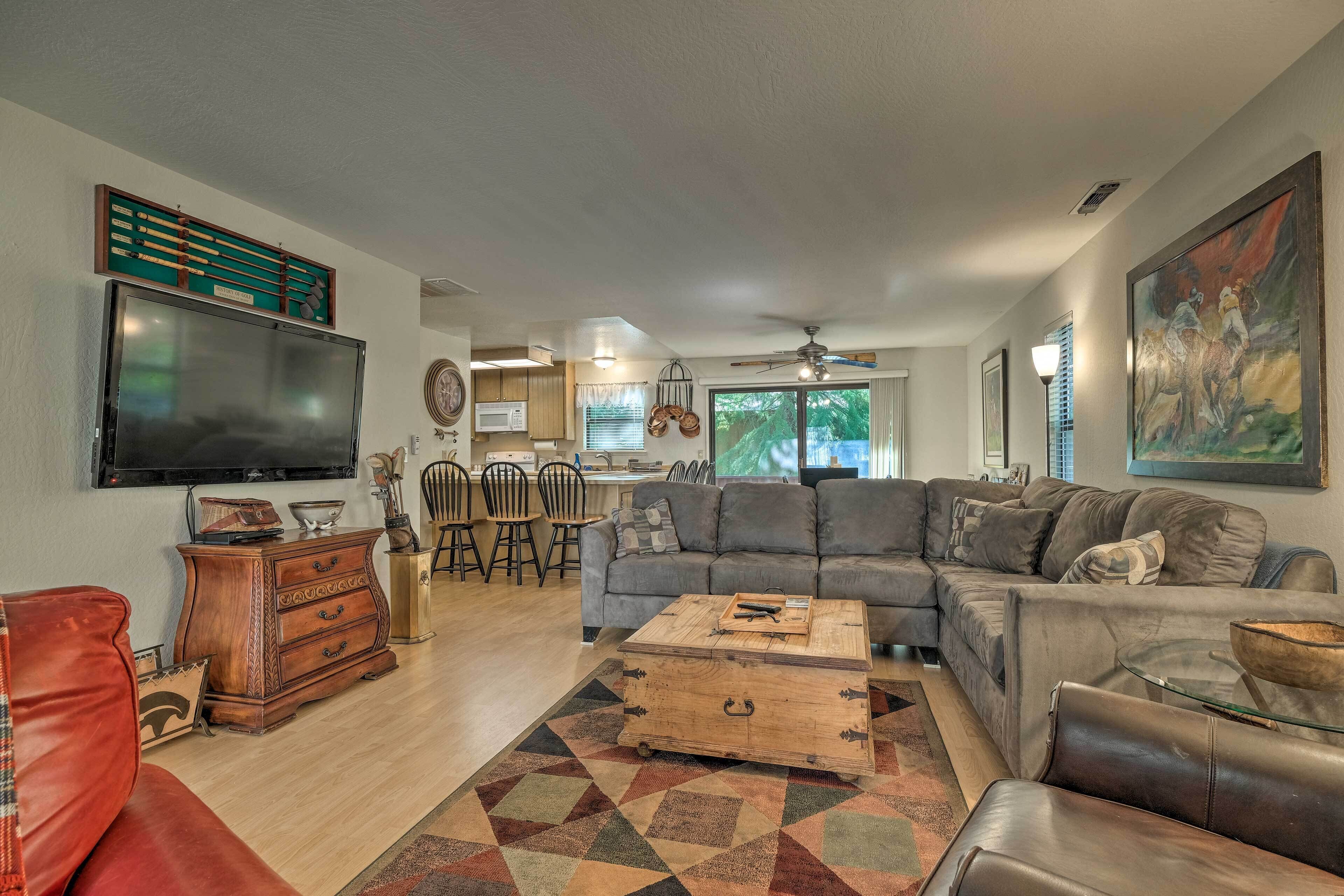 A living room with a sectional sofa, a coffee table, and a TV mounted on the wall.