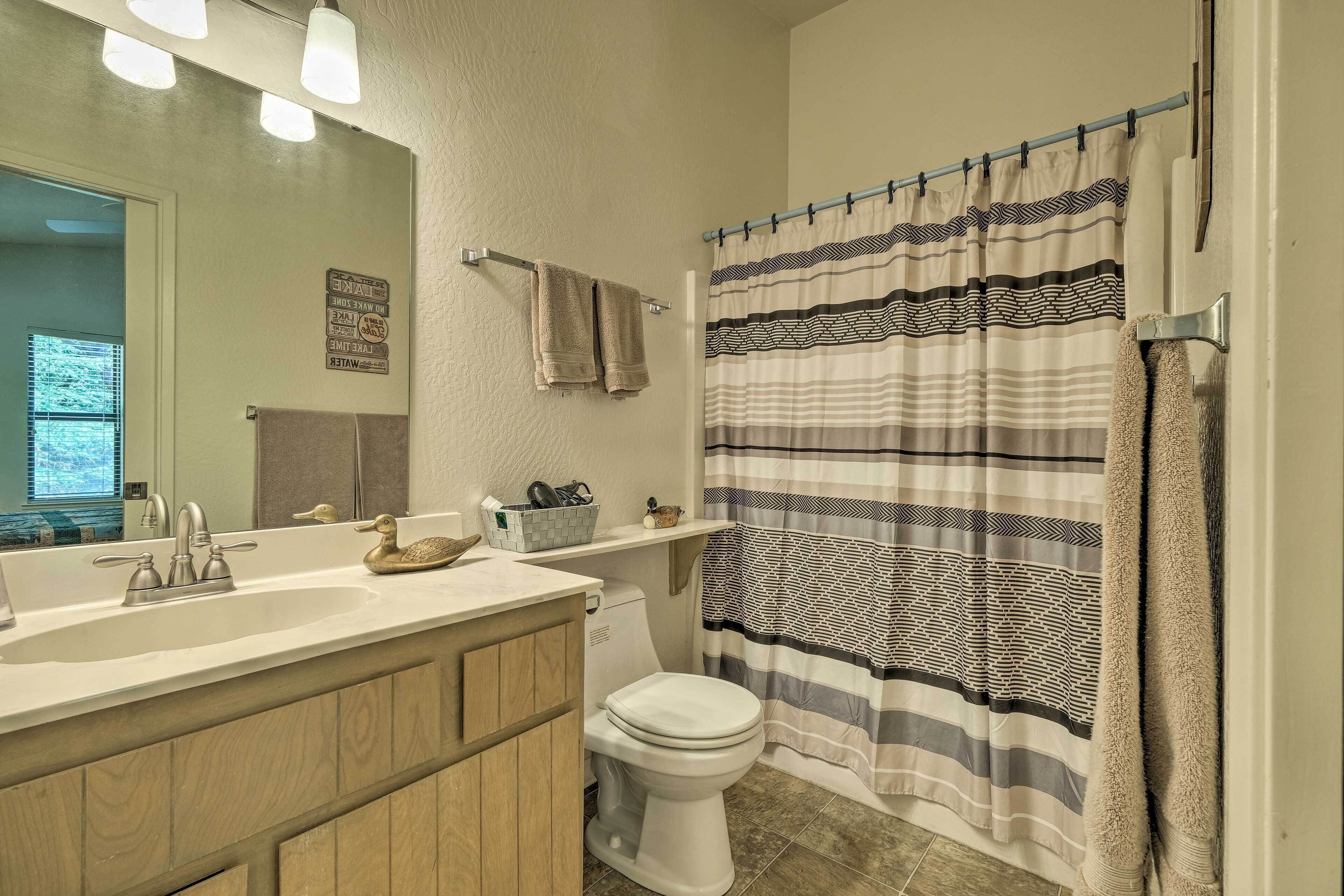 A bathroom with a sink, toilet, and shower curtain.