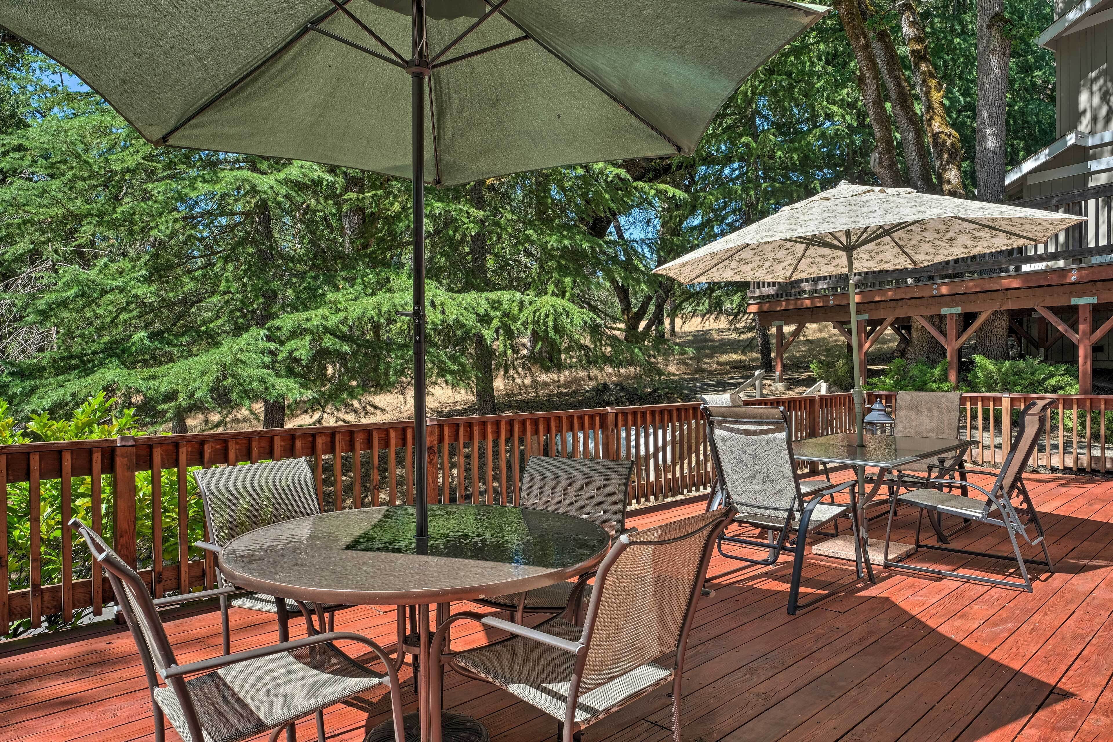 A wooden deck with a round table and chairs, surrounded by a wooden railing.