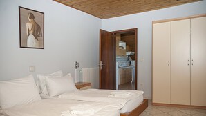 A bedroom with two beds, a wooden wardrobe, and a kitchen visible through an open door. - APP4 Romantic villa with pool - 5 min from the beach! (Novigrad)