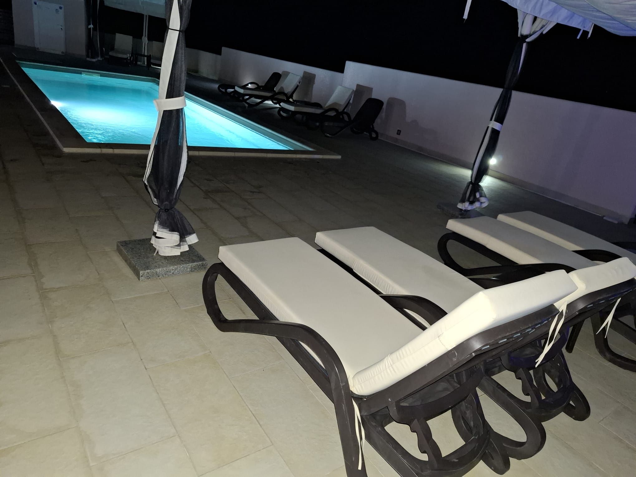 Un espace aménagé au bord de la piscine, avec des chaises longues et une piscine.