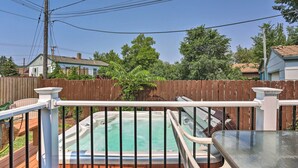 A hot tub on a wooden deck with a metal railing, surrounded by a wooden fence and greenery. - Rapid City Home w/ Patio by Canyon Lake Park! (Rapid City)