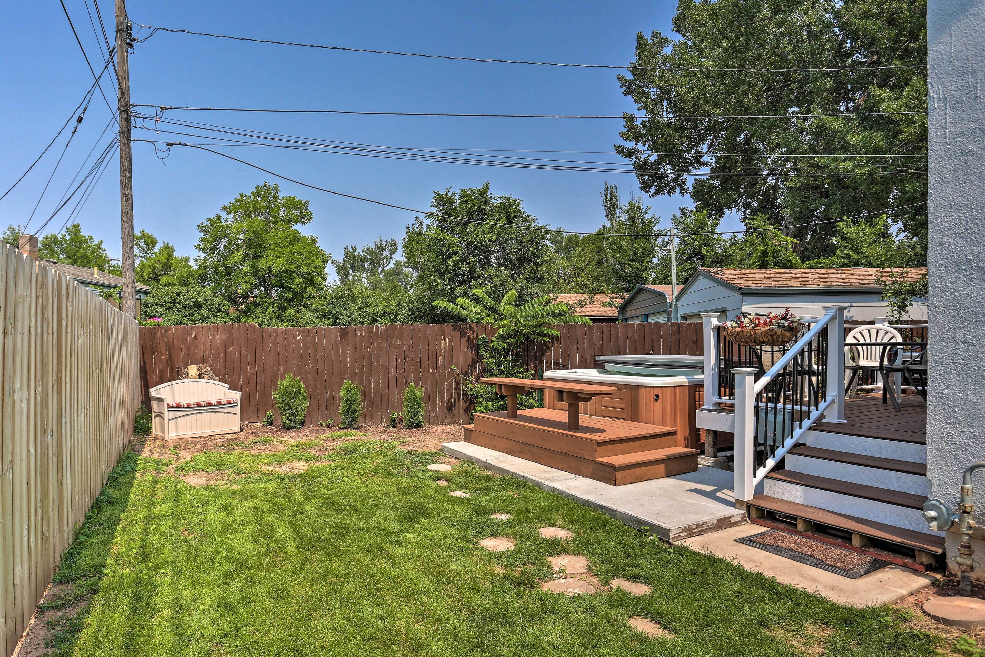 A backyard with a wooden deck, a hot tub, and a patio area with outdoor furniture.